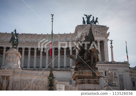 Altar of the Fatherland, Monument National Vittorio Emanuele II, Rome, Italy. Bronze statue of Victor Emmanuel II in front of grand white marble monument with patriotic flag and visitors. Altar of the Fatherland, Monument National Vittorio Emanuele II, Rome, Italy. Bronze statue of Victor Emmanuel II in front of grand white marble monument with patriotic flag and visitors. 113526036
