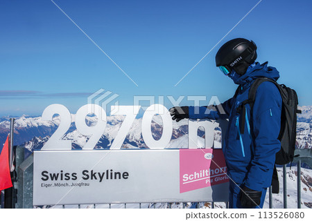 Person at Murren ski resort, Switzerland next to 2970m sign pointing at the altitude marker. Swiss Skyline with Eiger, Monch, Jungfrau peaks. Ideal skiing conditions with snow covered mountains. Person at Murren ski resort, Switzerland next to 2970m sign pointing at the altitude marker. Swiss Skyline with Eiger, Monch, Jungfrau peaks. Ideal skiing conditions with snow covered mountains. 113526080