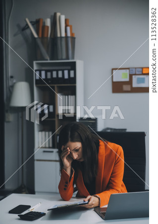 Portrait of tired young business Asian woman work with documents tax laptop computer in office. Sad, unhappy, Worried, Depression, or employee life stress concept 113528362