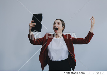 Photo of young attractive happy positive woman hold pc tablet hand touch chin isolated over grey color background 113528435