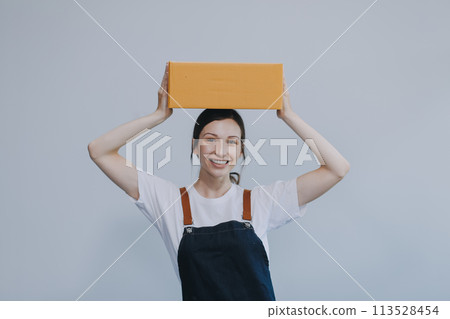 Smiling Asian woman in casual clothes holding a cardboard box mockup while standing against an isolated white background. shipping business concept Smiling Asian woman in casual clothes holding a cardboard box mockup while standing against an isolated white background. shipping business concept 113528454