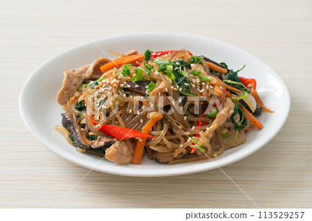 japchae or stir-fried Korean vermicelli noodles with vegetables and pork topped with white sesame 113529257