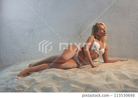 Sexy woman in white lingerie lying on sand Sexy woman in white lingerie lying on sand 113530698