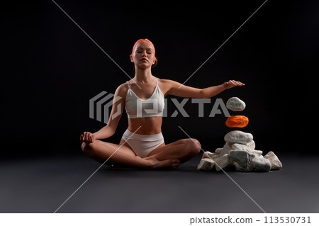 Young woman sitting on the floor and telekinesis the rock Young woman sitting on the floor and telekinesis the rock 113530731