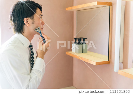 Young Asian businessman in a suit shaving in the bathroom before going to work in the morning 113531893
