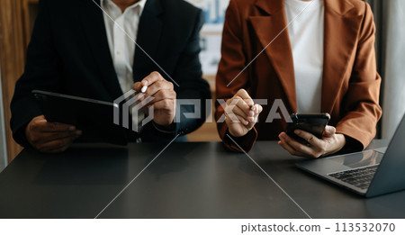 Business documents on office table with smart phone and calculator digital tablet and graph business with social network diagram and two colleagues discussing data . 113532070
