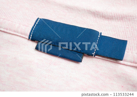 Blank blue laundry care clothes label on pink shirt fabric texture background 113533244