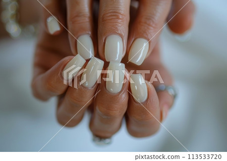 Close-up shot of professionally manicured hands featuring glossy neutral nail polish 113533720