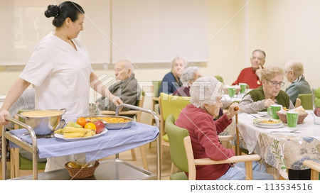 Cook entering with food to the dining room of geriatric 113534516