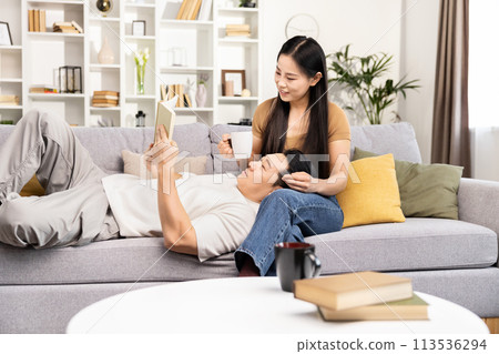 Couple Relaxing on Sofa With Book and Coffee at Home 113536294