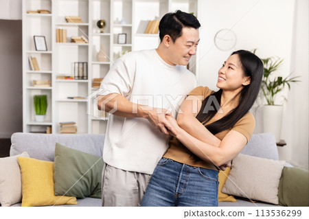 Happy Asian Couple Dancing and Singing at Home Together 113536299