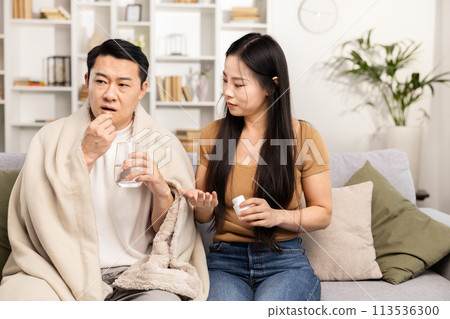Caring Woman Giving Medicine to Sick Man at Home Caring Woman Giving Medicine to Sick Man at Home 113536300
