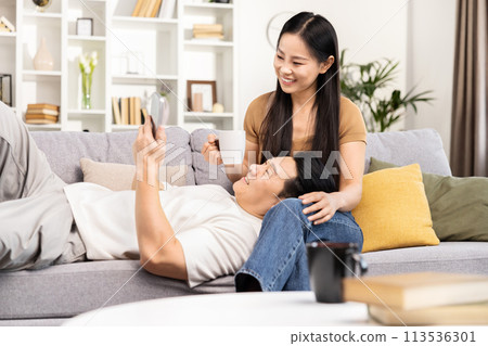 Happy Asian Couple Relaxing and Using Smartphone at Home Happy Asian Couple Relaxing and Using Smartphone at Home 113536301