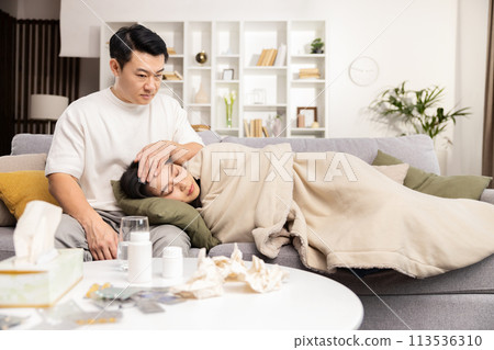 Caring Man Comforts Sick Woman Resting on Couch at Home 113536310