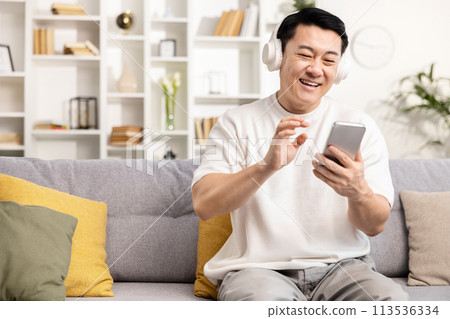 Happy Man Using Smartphone With Headphones at Home 113536334