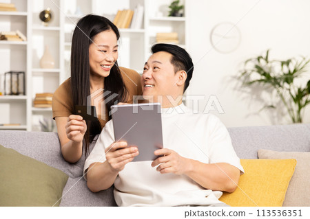 Couple Shopping Online Together on a Comfortable Sofa Couple Shopping Online Together on a Comfortable Sofa 113536351