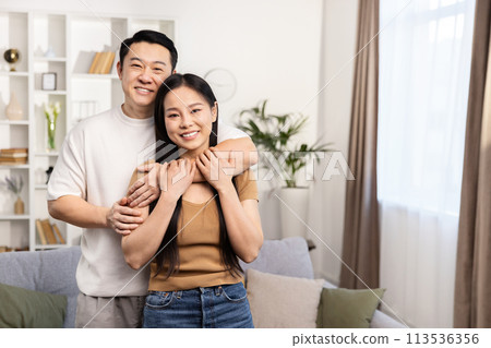 Happy Asian Couple Embracing in Cozy Living Room Happy Asian Couple Embracing in Cozy Living Room 113536356