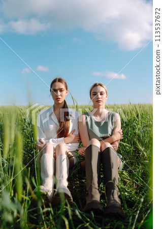 Two Beautiful woman in the green field. Nature, vacation, relax and lifestyle. Summer landscape. Two Beautiful woman in the green field. Nature, vacation, relax and lifestyle. Summer landscape. 113537672
