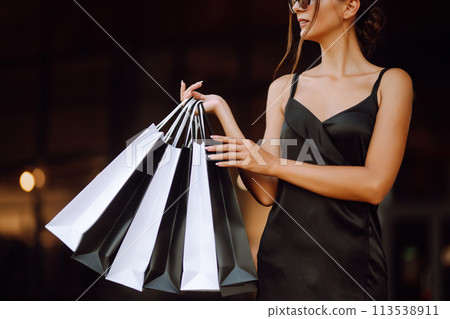 Shopping bags in the hands. Fashion woman with packages after shopping. Black friday, sale. 113538911