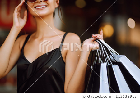 Fashion woman enjoying shopping. Elegant woman wears black dress holding black and white shopping bags. Fashion woman enjoying shopping. Elegant woman wears black dress holding black and white shopping bags. 113538913