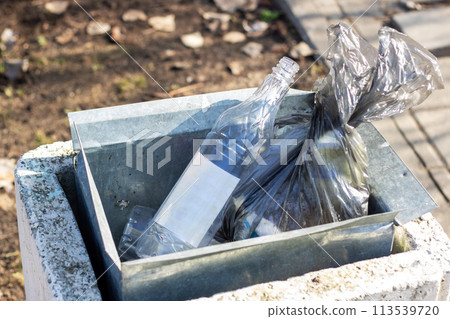 Black big garbage cans on asphalt closeup Black big garbage cans on asphalt closeup 113539720
