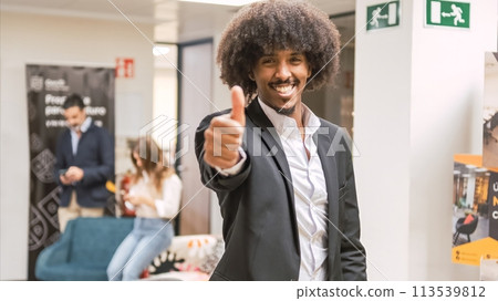 Happy confident creative businessman showing thumbs up in office Happy confident creative businessman showing thumbs up in office 113539812