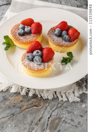 Japanese style sluffy souffle pancake dessert with blueberry and strawberry close-up on a plate. Vertical Japanese style sluffy souffle pancake dessert with blueberry and strawberry close-up on a plate. Vertical 113539848