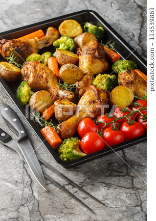 Healthy food baked chicken drumstick with broccoli, potatoes, tomatoes and carrots close-up on a sheet pan. Vertical Healthy food baked chicken drumstick with broccoli, potatoes, tomatoes and carrots close-up on a sheet pan. Vertical 113539861