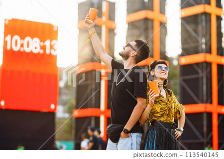 Lovely couple having fun at festival. Young friends with beer at beach party. Summer holiday, vacation. Lovely couple having fun at festival. Young friends with beer at beach party. Summer holiday, vacation. 113540145