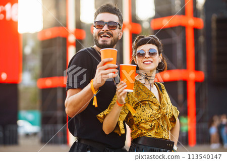 Lovely couple having fun at festival. Young friends with beer at beach party. Summer holiday, vacation. Lovely couple having fun at festival. Young friends with beer at beach party. Summer holiday, vacation. 113540147