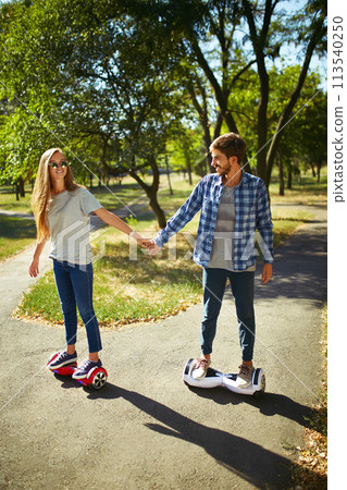 Young man and woman riding on the Hoverboard in the park. content technologies. a new movement. 113540250