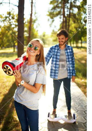 Young man and woman riding on the Hoverboard in the park. content technologies. a new movement. Young man and woman riding on the Hoverboard in the park. content technologies. a new movement. 113540251