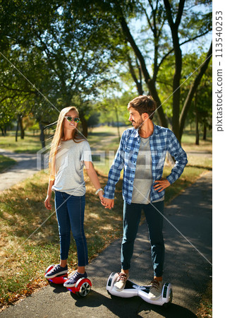 Young man and woman riding on the Hoverboard in the park. content technologies. a new movement. 113540253