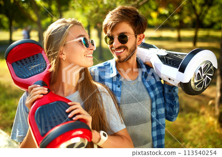 Young man and woman riding on the Hoverboard in the park. content technologies. a new movement. 113540254