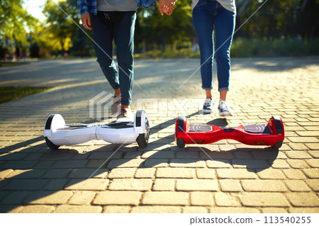 Young man and woman riding on the Hoverboard in the park. content technologies. a new movement. 113540255