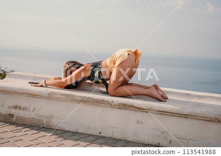 Woman park yoga. Side view of free calm bliss satisfied woman with long hair standing in morning park with yoga position against of sky by the sea. Healthy lifestyle outdoors in park, fitness concept. Woman park yoga. Side view of free calm bliss satisfied woman with long hair standing in morning park with yoga position against of sky by the sea. Healthy lifestyle outdoors in park, fitness concept. 113541988
