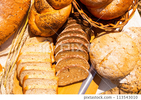 Lot of different flavored bread, wheat, rye, on the table in the field outside 113543010