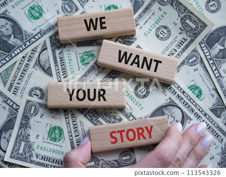 We want your story symbol. Concept words We want your story on wooden blocks. Businessman hand. Beautiful dollar background. Business and We want your story concept. Copy space. 113543326