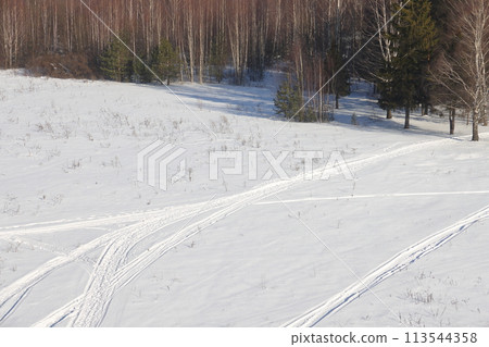 Deserted winter landscape. A path of footprints stretches across the pure white snow Deserted winter landscape. A path of footprints stretches across the pure white snow 113544358