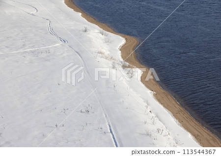 Deserted winter landscape. A path of footprints stretches across the pure white snow. Deserted winter landscape. A path of footprints stretches across the pure white snow. 113544367