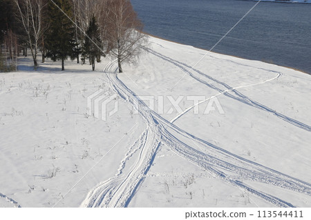 Deserted winter landscape. A path of footprints stretches across the pure white snow Deserted winter landscape. A path of footprints stretches across the pure white snow 113544411