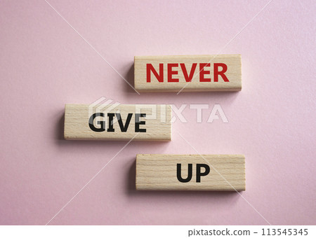 Never give up symbol. Concept words Never give up on wooden blocks. Beautiful pink background. Business and Never give up concept. Copy space. 113545345