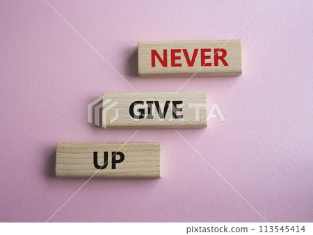 Never give up symbol. Concept words Never give up on wooden blocks. Beautiful pink background. Business and Never give up concept. Copy space. 113545414