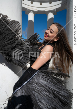 a girl in a black suit and angel wings on the background of the rotunda and the sky a girl in a black suit and angel wings on the background of the rotunda and the sky 113545529