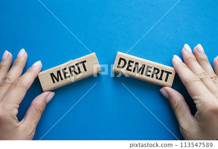 Merit or Demerit symbol. Concept word Merit or Demerit on wooden blocks. Businessman hand. Beautiful blue background. Business and Merit or Demerit concept. Copy space 113547589