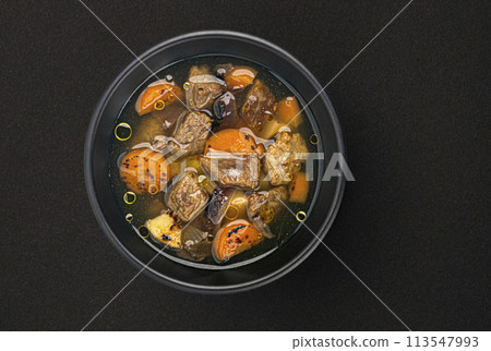Beef stew with broth, soup with meat and vegetable on black background with copy space, top view 113547993
