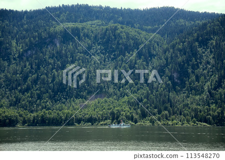 boat goes along the shore of a mountain lake boat goes along the shore of a mountain lake 113548270