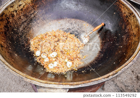 Appetizing traditional Uzbek pilaf in a large cauldron 113549292