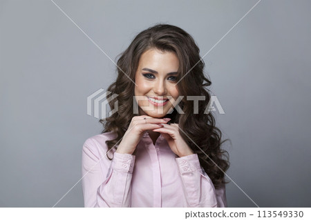Pretty woman with long healthy wavy hair, cute smile and make-up looking at camera Pretty woman with long healthy wavy hair, cute smile and make-up looking at camera 113549330