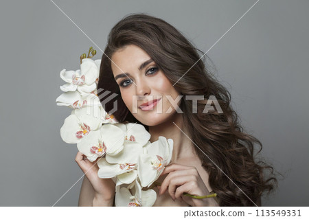 Charming young brunette female model with long brown wavy hair and makeup closeup portrait 113549331